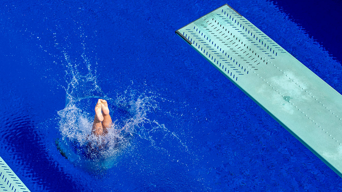 Atleta finalizando salto em trampolim na piscina