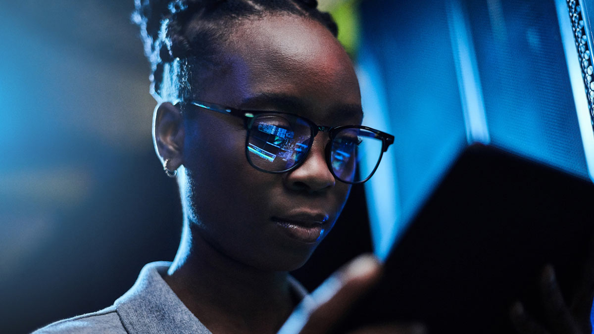 jovem engenheira usando um tablet digital enquanto trabalhava em uma sala de servidor