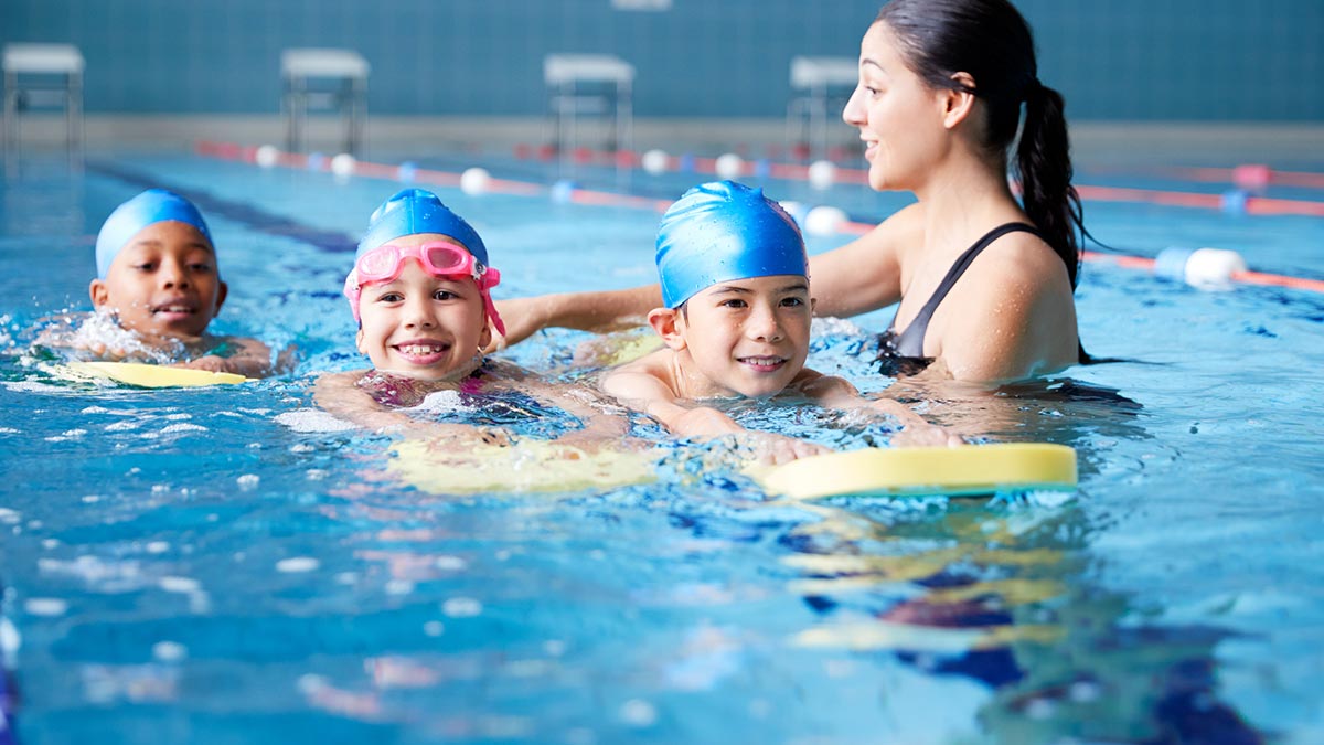 crianças na piscina aprendendo natação com professora