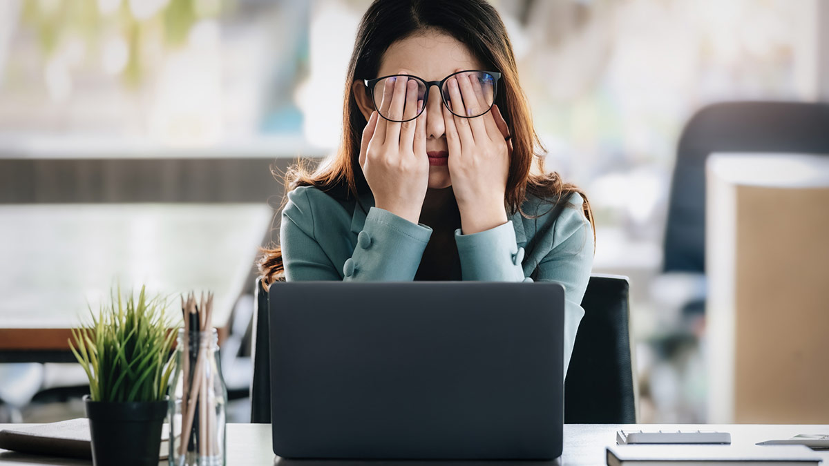 Mulher sofrendo de Burnout no trabalho em um escritorio.