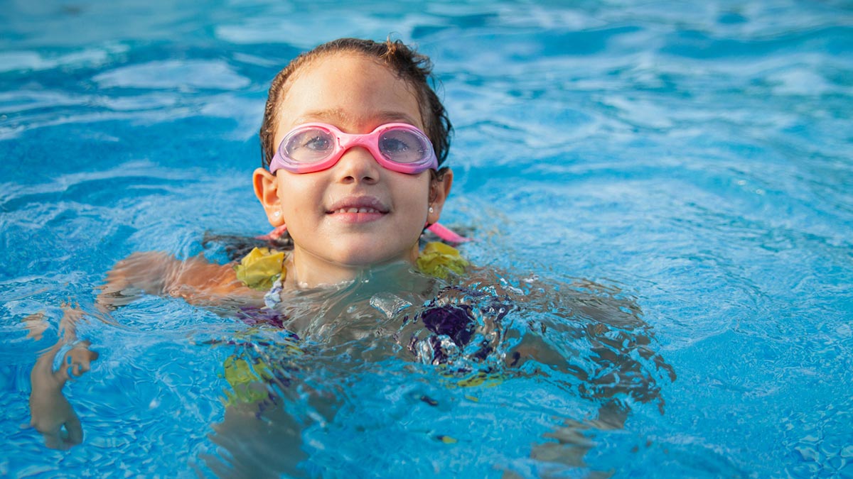 Menina na piscina com utlizando óculos de natação