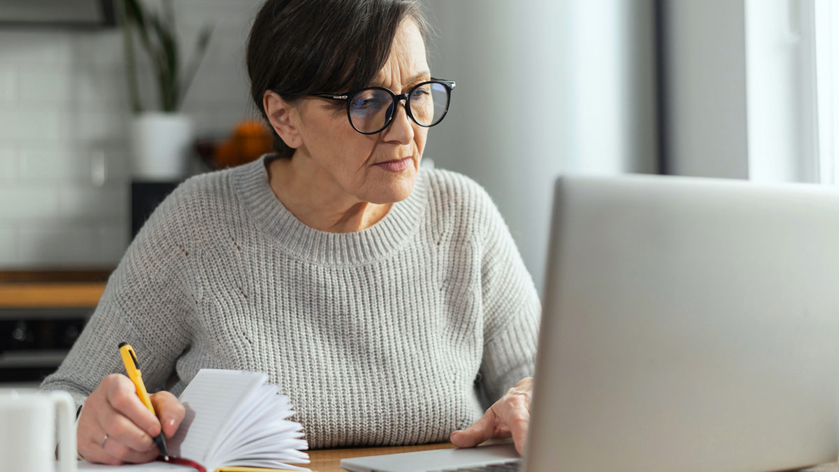 Mulher a utilizar laptop e fazendo anotações