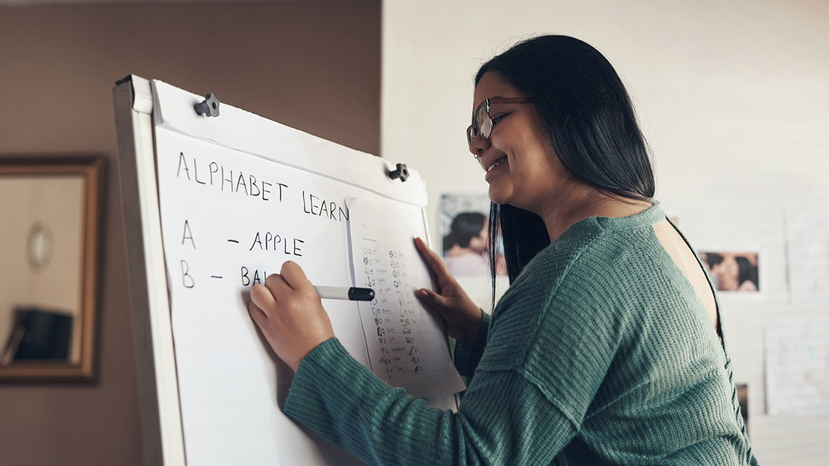 Mulher escrevendo em painel em inglês.