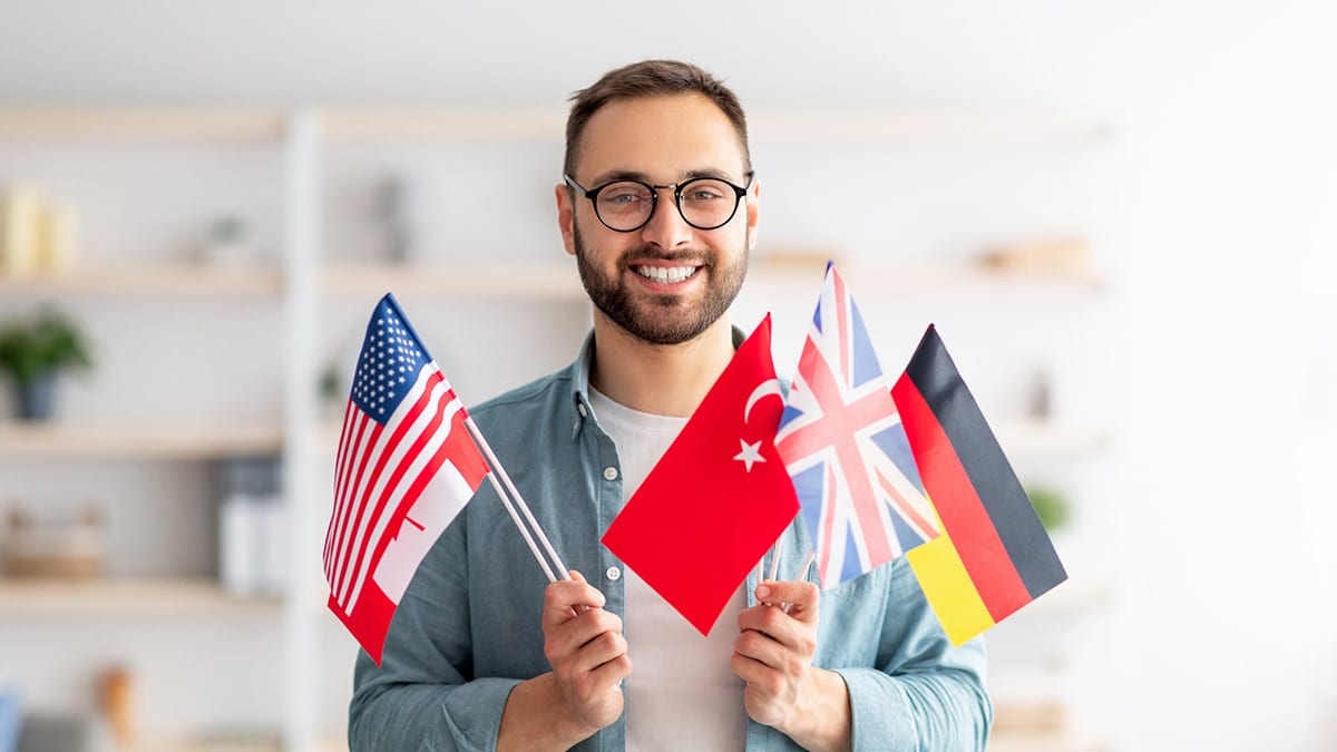 Homem a segurar bandeira de vários países do mundo.