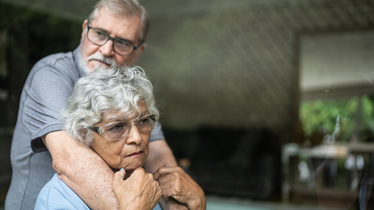 Casal de terceira idade tristes sentados no sofá de uma sala