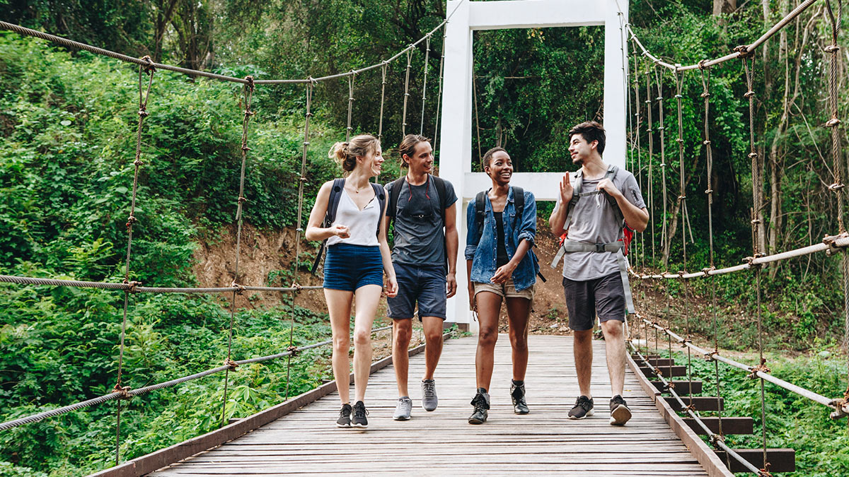 Foto de amigos andando sob uma ponte em um parque